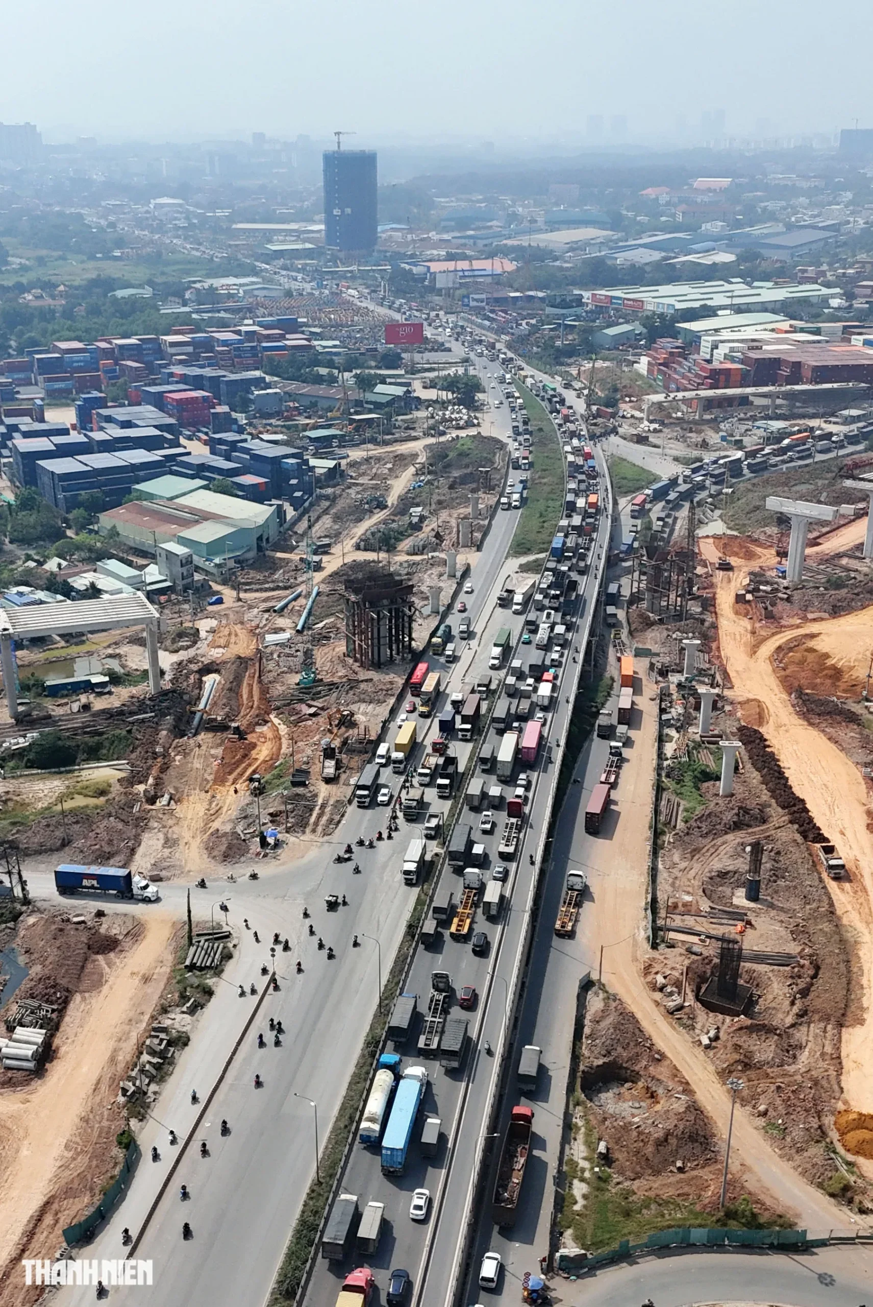 Công trường thi công dọc xa lộ Hà Nội với các trụ cầu đang xây dựng bên cạnh dòng xe đông đúc